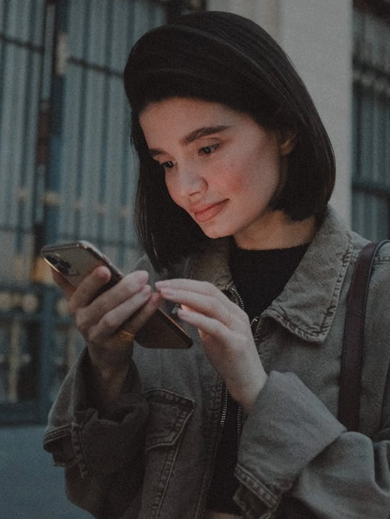 Jeune femme consultant son smartphone, illustrant un cas client lié à la délivrabilité email et à la réception des messages.
