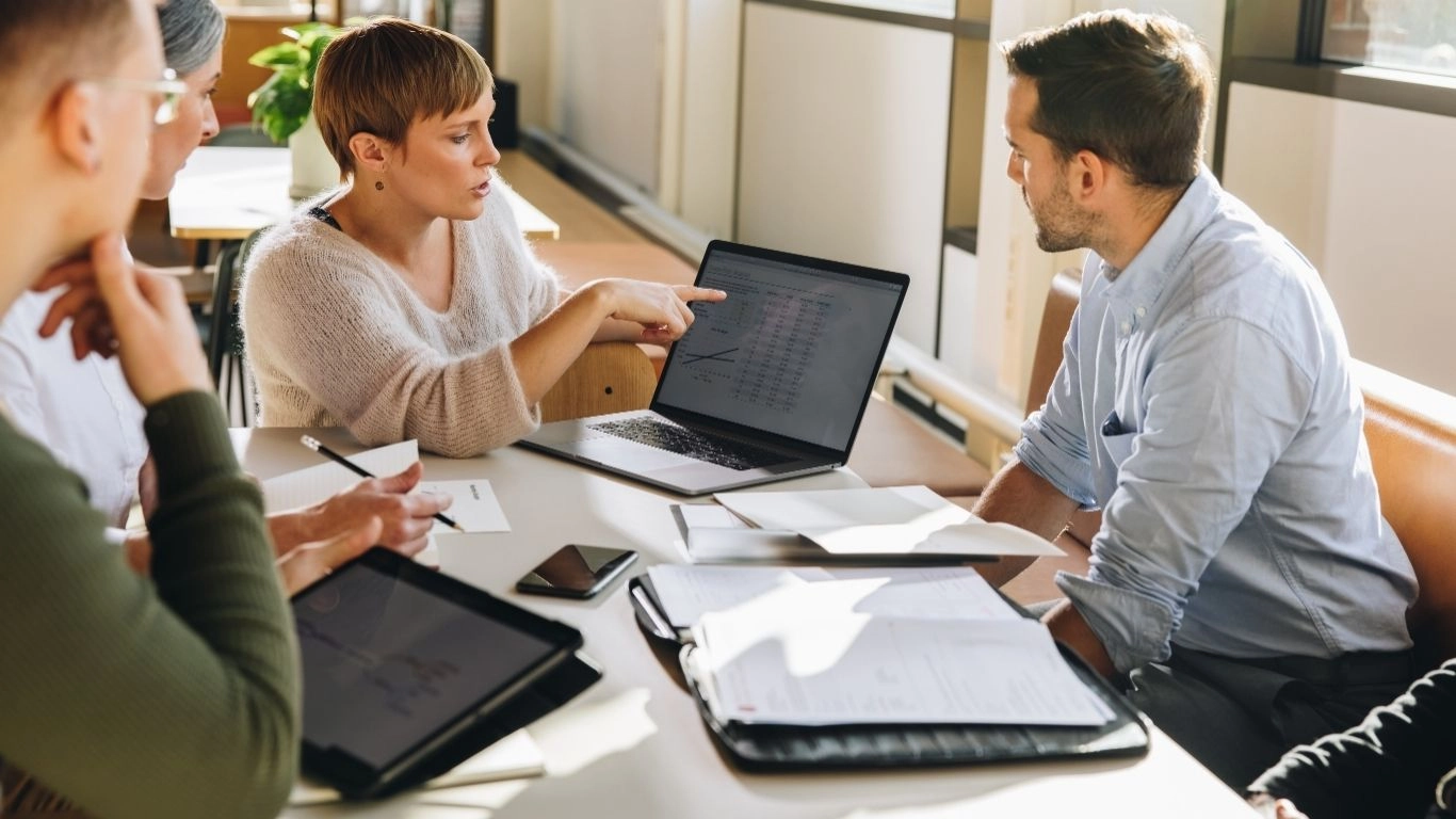 Équipe en réunion autour d’un ordinateur, illustrant l’accompagnement à la connectivité et l’intégration des données.