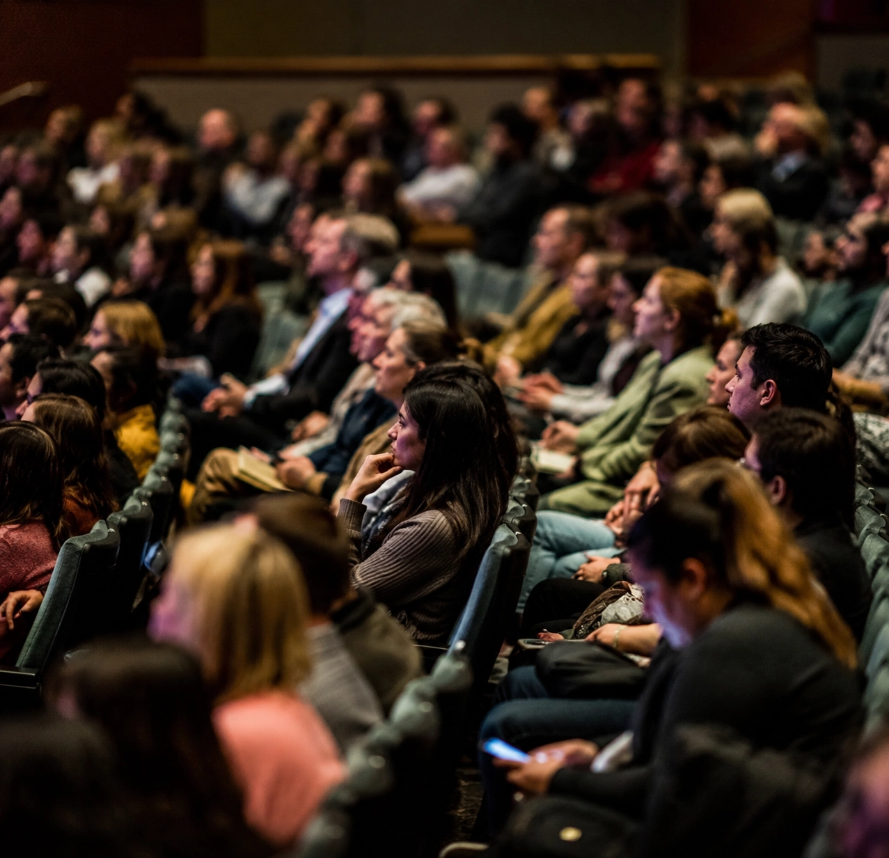 Audience assise dans une salle de conférence, attentive à une présentation ou un événement professionnel.