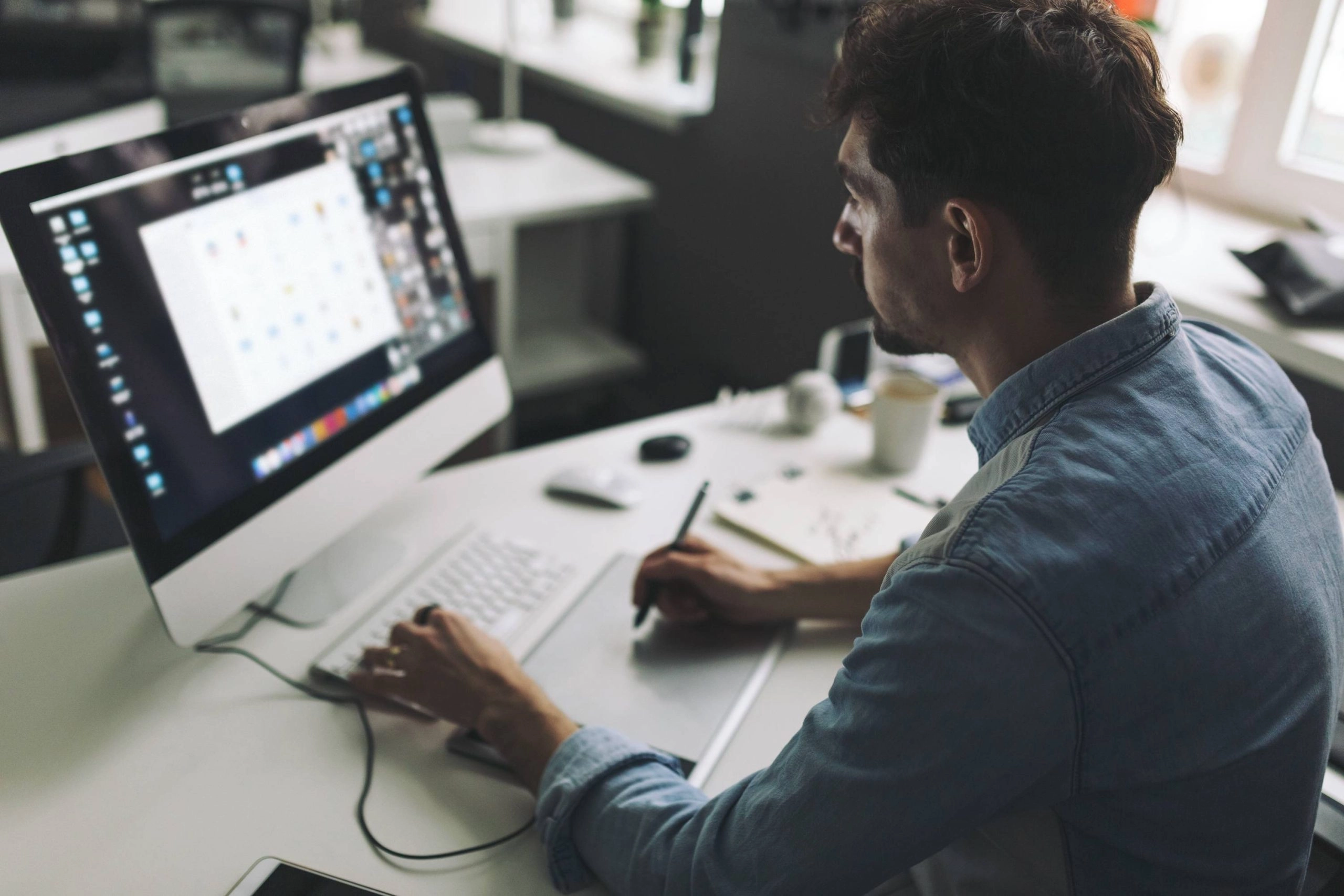 Designer travaillant sur ordinateur avec une tablette graphique pour créer et intégrer des contenus e-mail et web.