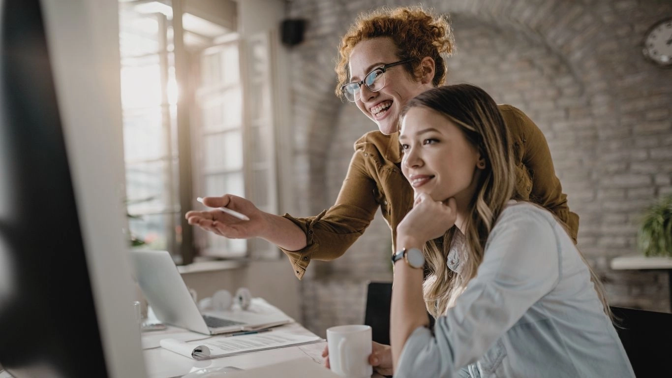 Deux professionnelles échangeant devant un ordinateur, illustrant une formation dédiée à l’accessibilité numérique appliquée à l’emailing.