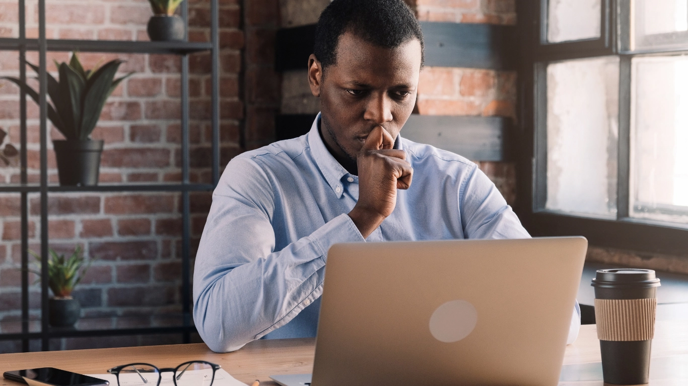 Professionnel concentré devant son ordinateur portable dans un bureau, analysant ses actions marketing digitales.
