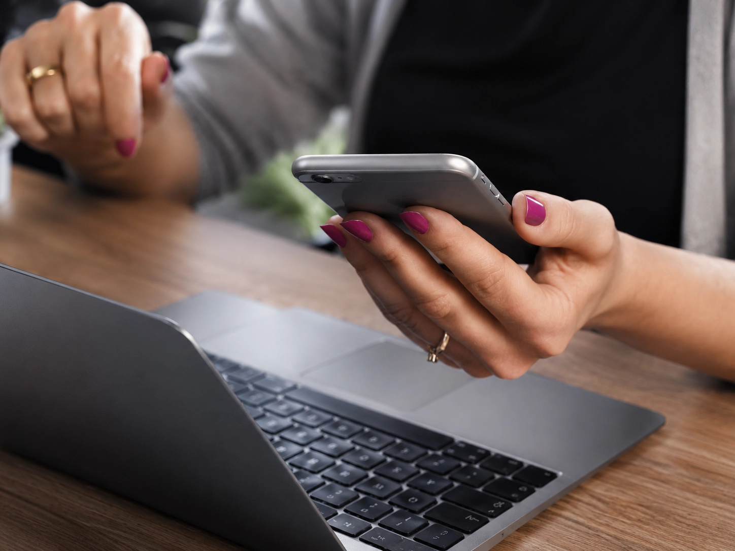 Personne consultant un smartphone à côté d’un ordinateur portable, illustrant la gestion mobile des communications digitales.