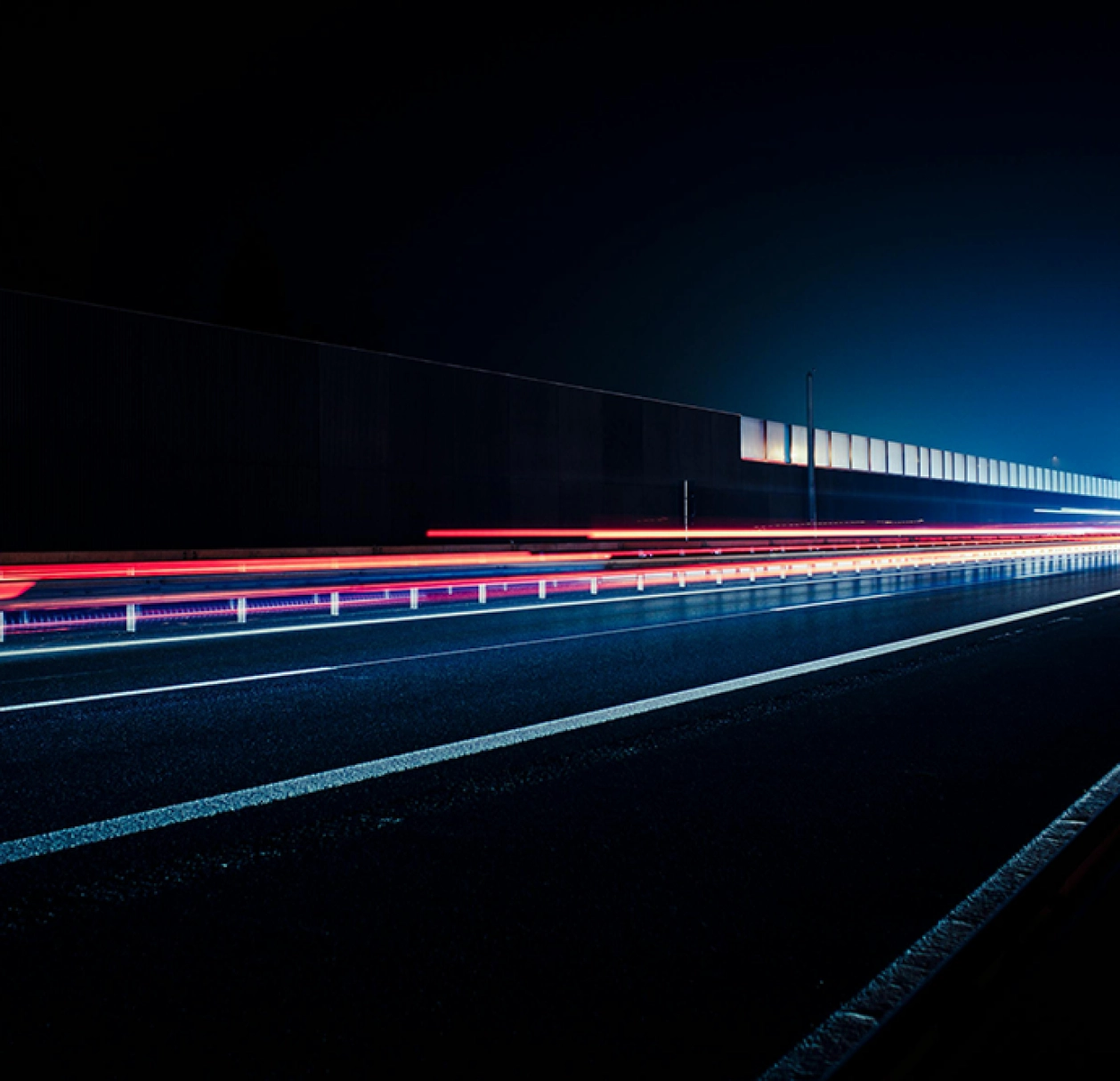 Traînées lumineuses sur une route de nuit, illustration de la rapidité et de la fiabilité des envois e-mail.