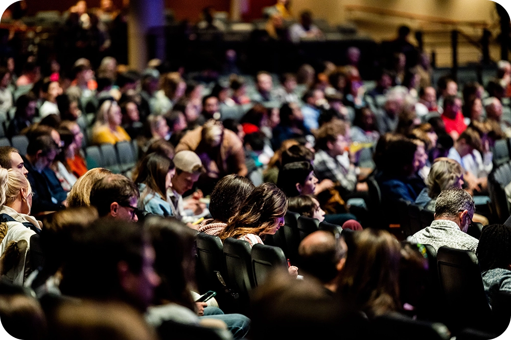 Audience réunie dans une salle de conférence, illustration de la communication avec différents publics.